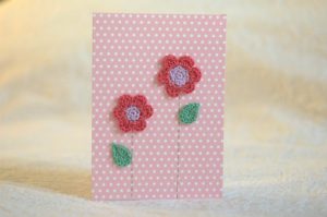 Hand made and hand stitched, pink and lilac crocheted flowers and green crocheted leaves greetings card. Left blank inside for your own message. Size w12.7 x h17.7cm