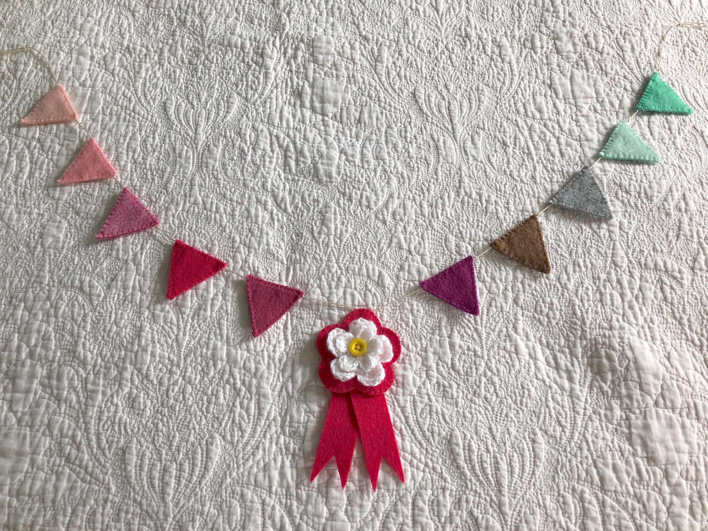 Hand stitched felt bunting with crocheted flower rosette centre.