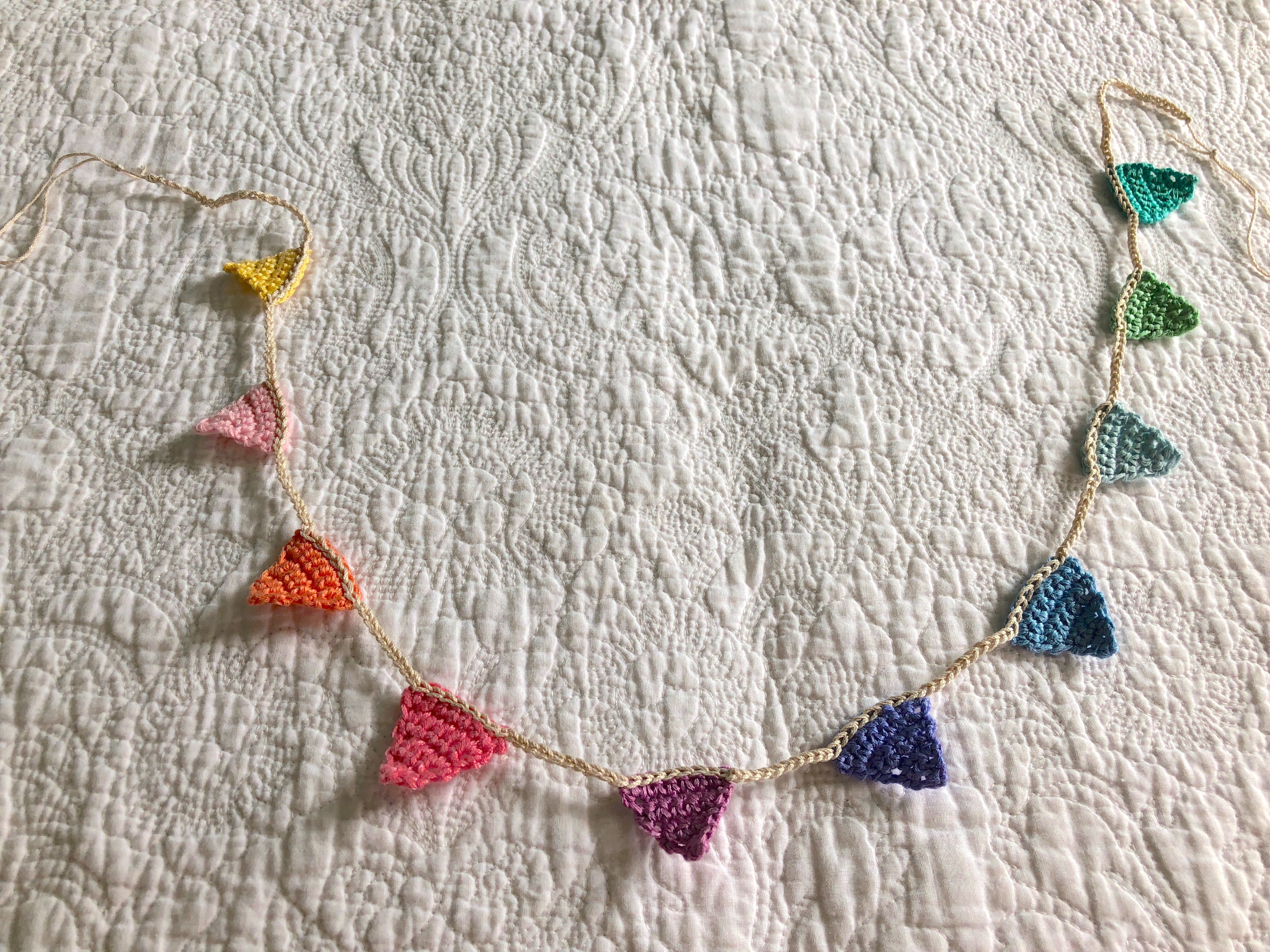 Tiny crocheted bunting in a rainbow of colours.