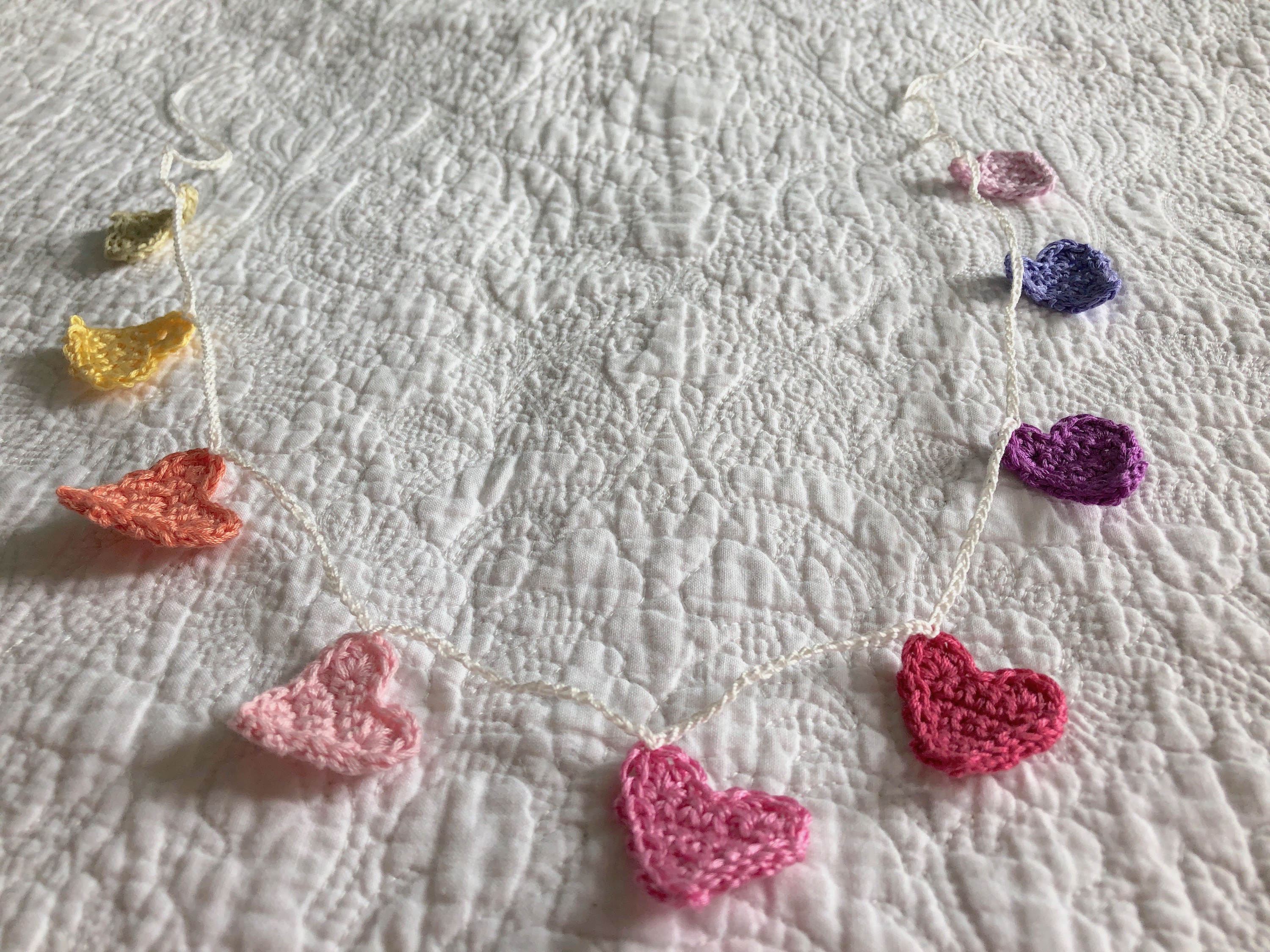 Tiny crocheted hearts bunting in a rainbow of colours.