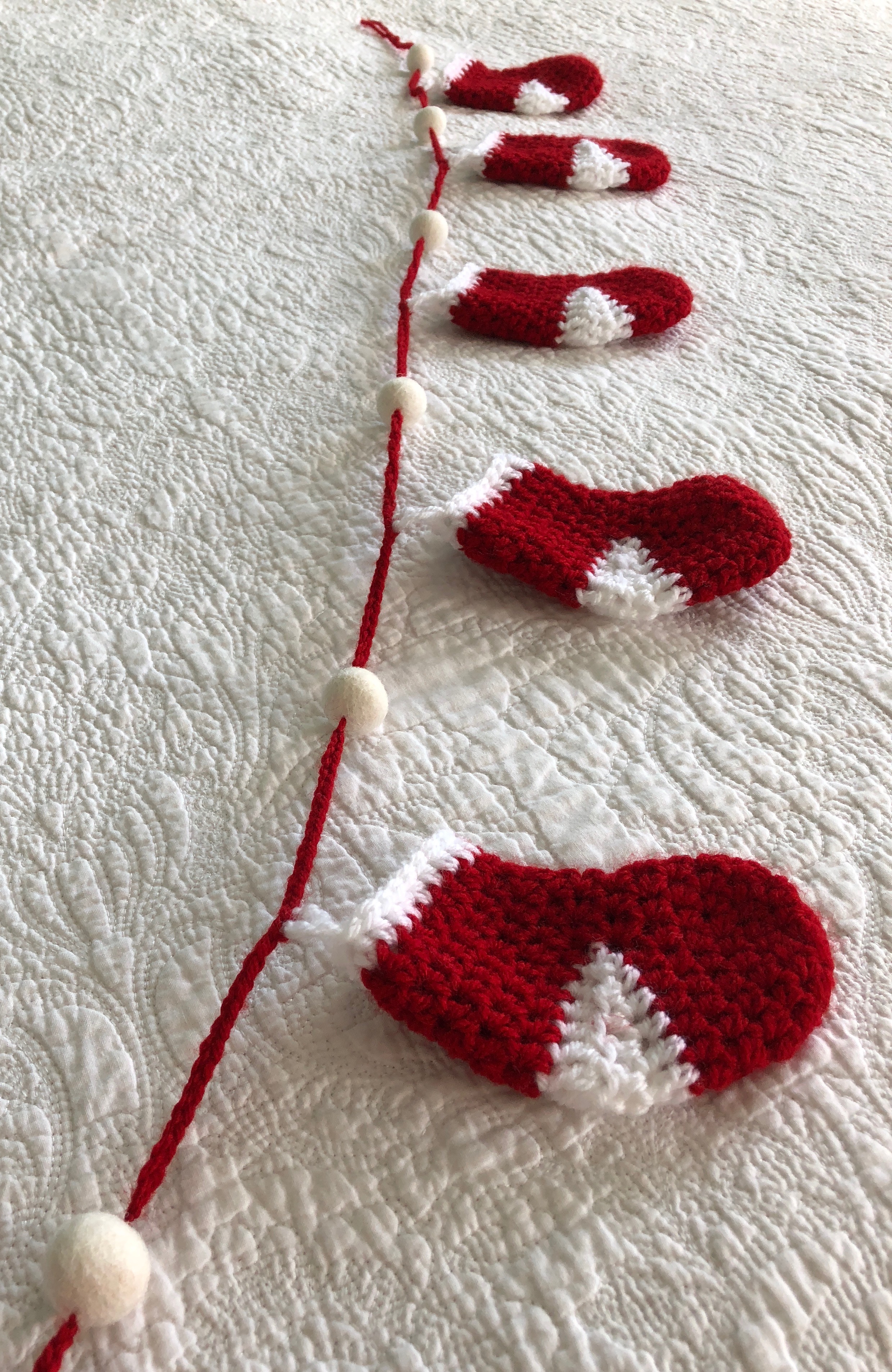 Handmade, crocheted, red and white stockings and white felt pom-pom garland.