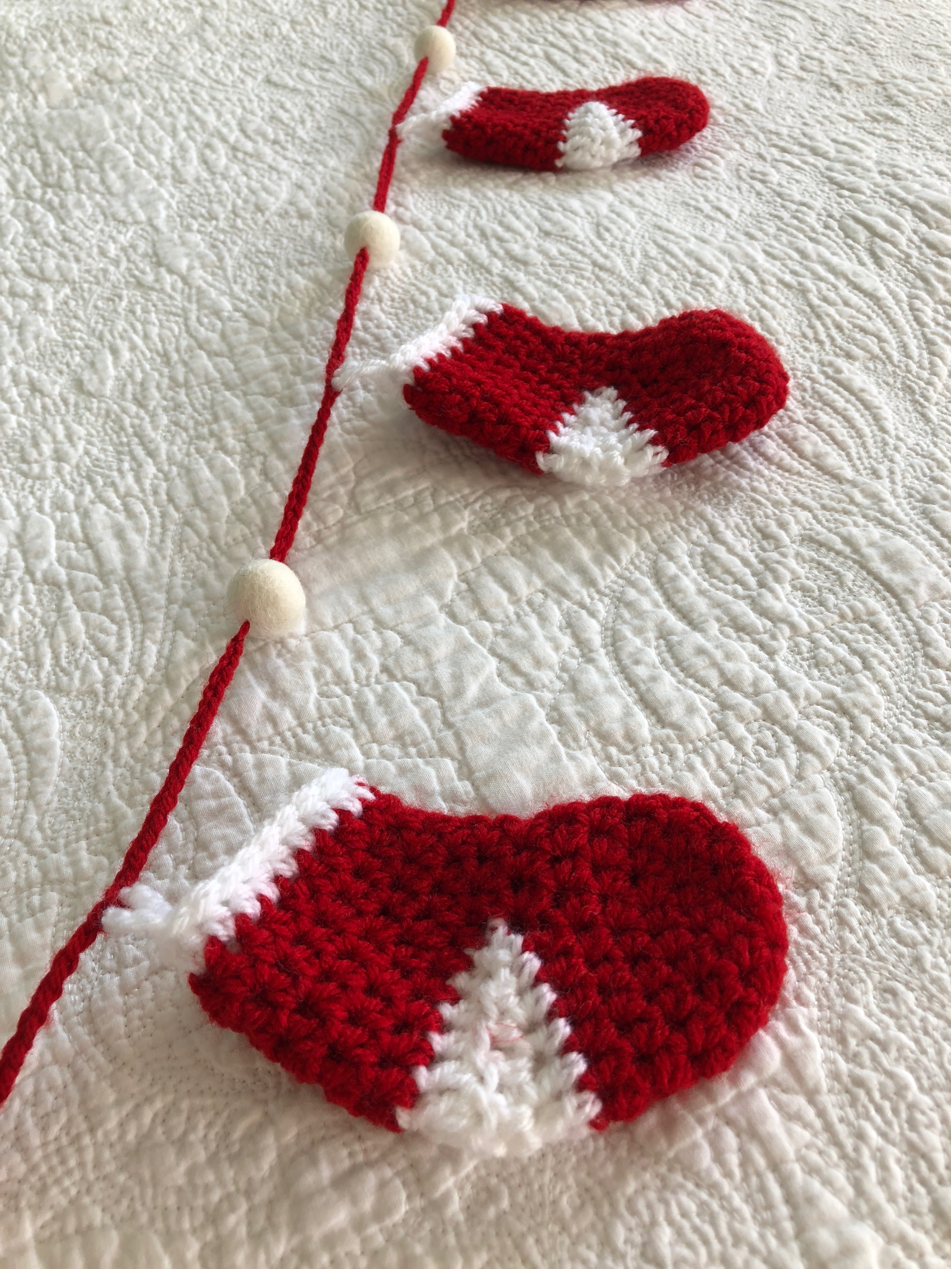 Handmade, crocheted, red and white stockings and white felt pom-pom garland.