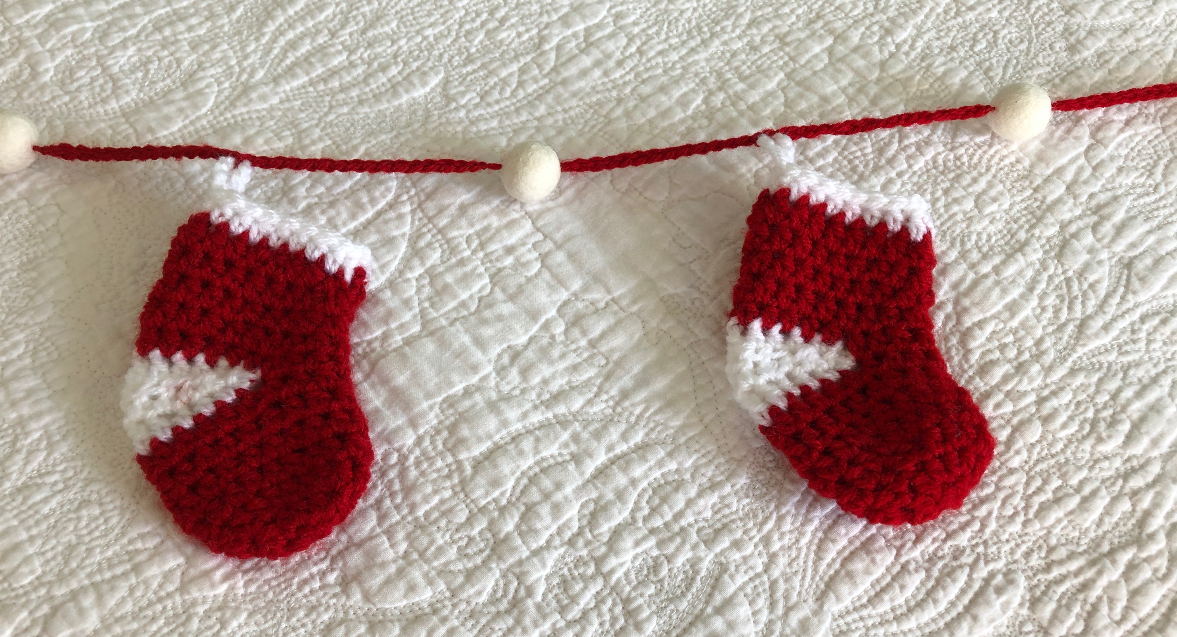 Handmade, crocheted, red and white stockings and white felt pom-pom garland.