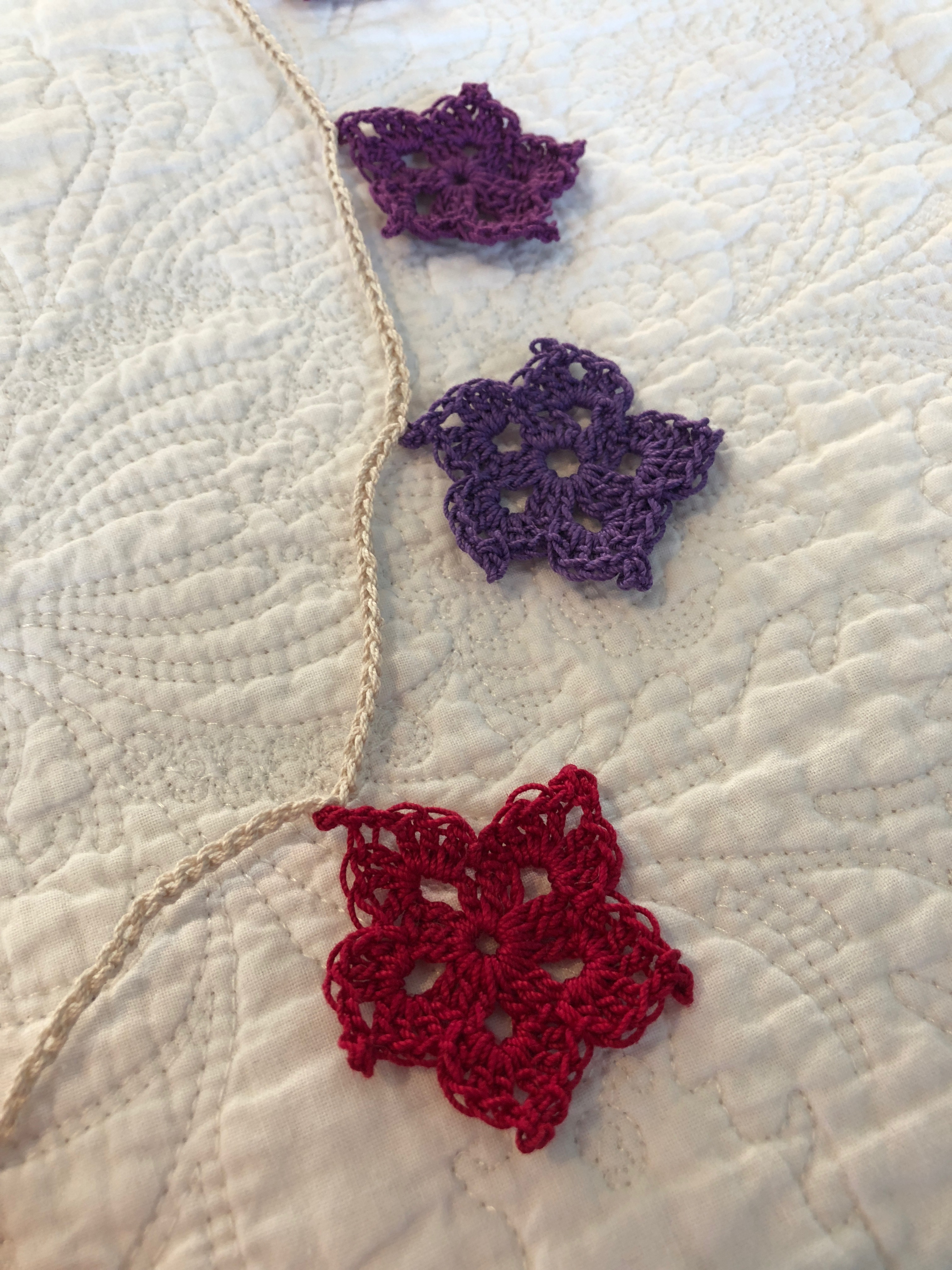 Hand made, crocheted, vintage style, cotton star garland in a gradient of red to purple shades.