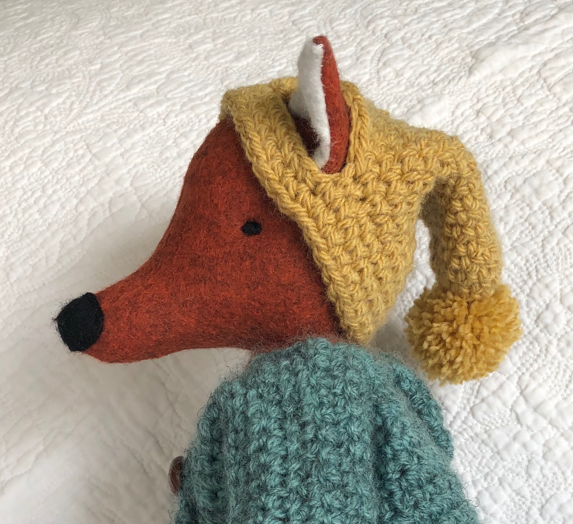 A handmade rusty brown felt fox with a green hand crocheted jacket, mustard yellow bobble hated little black felt boots. Fox pattern by Simone Gooding, crocheted clothes designed and made by me.