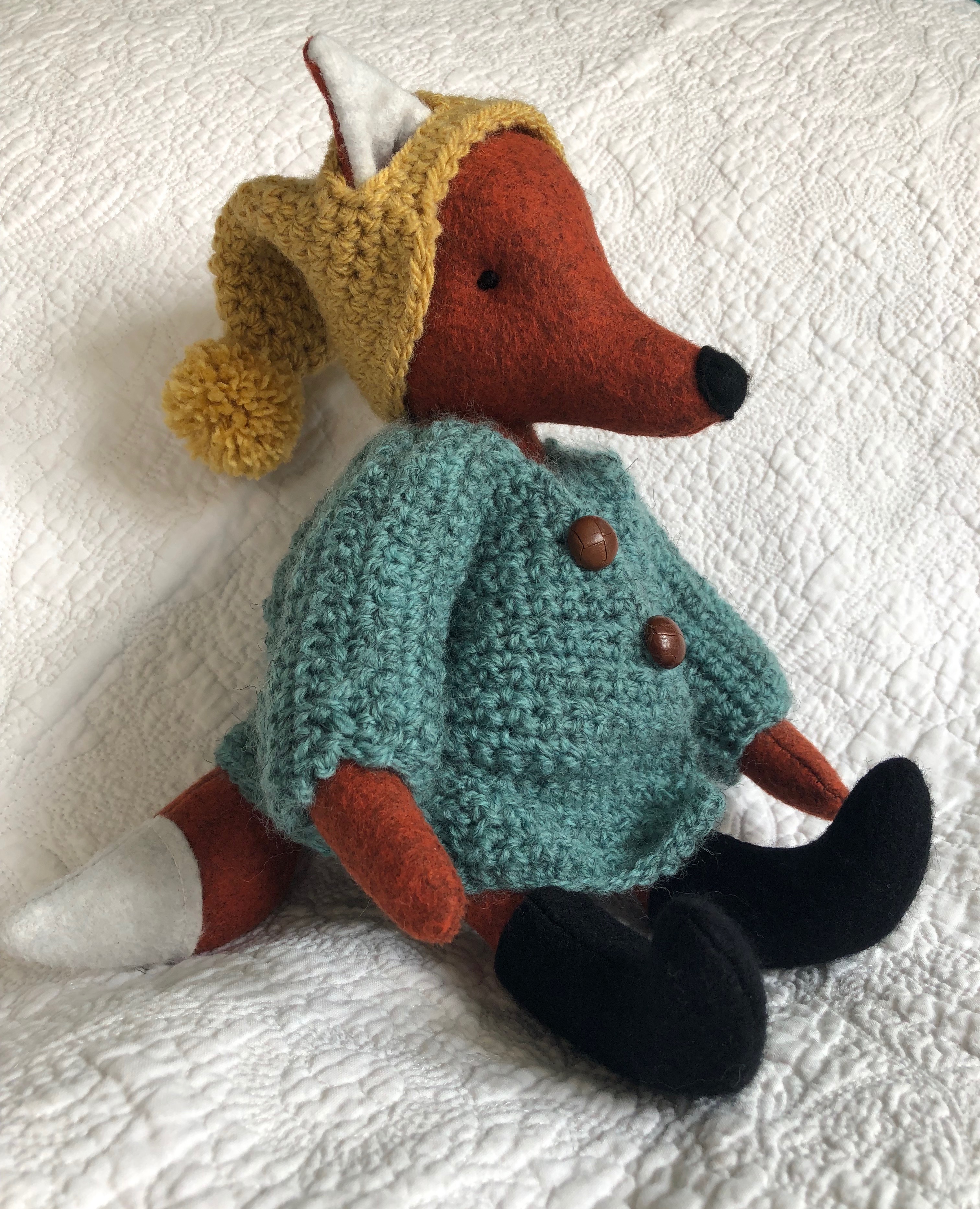 A handmade rusty brown felt fox with a green hand crocheted jacket, mustard yellow bobble hated little black felt boots. Fox pattern by Simone Gooding, crocheted clothes designed and made by me.