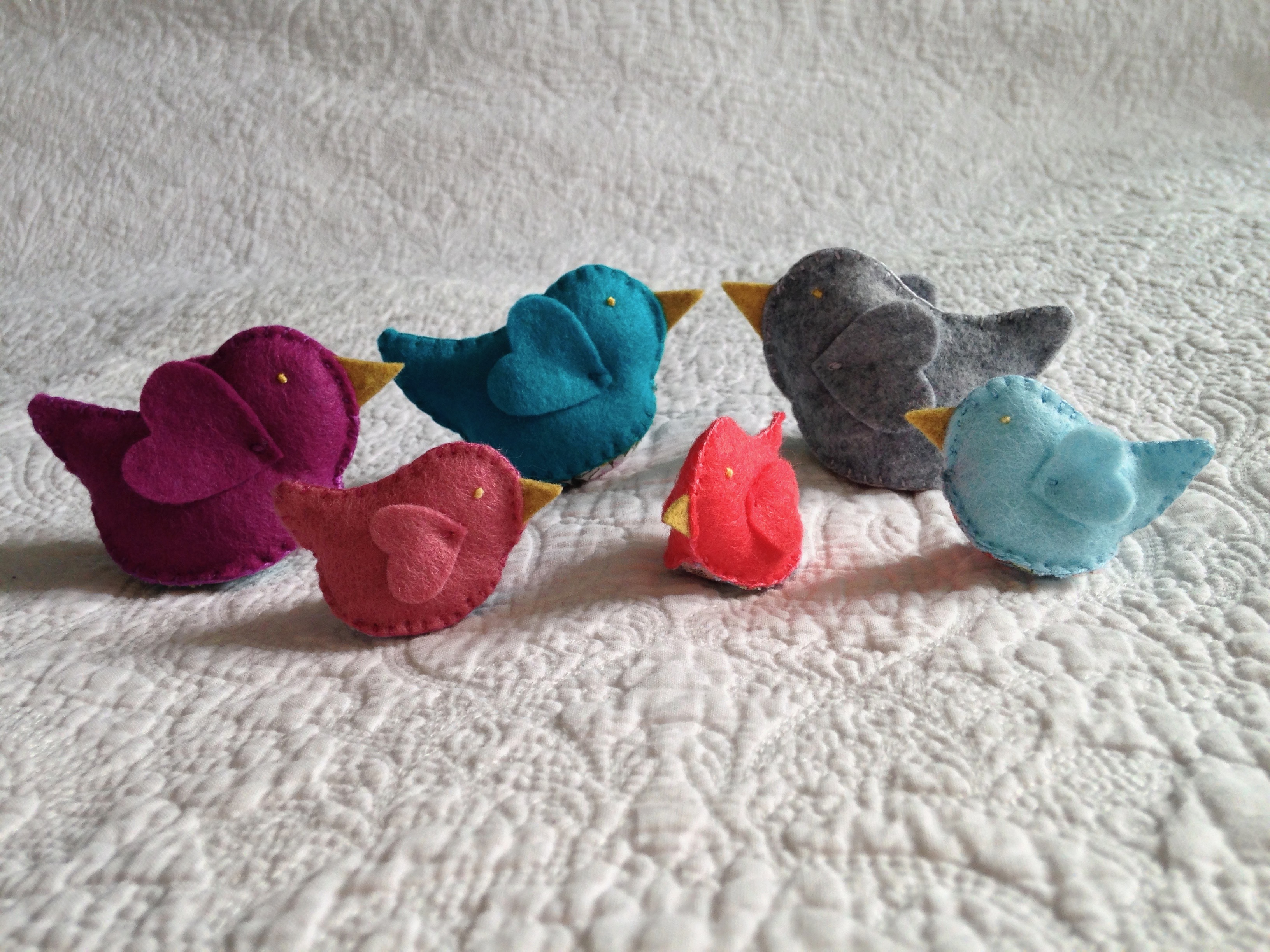 Colourful felt and fabric hand stitched little bird decorations in various colours.
