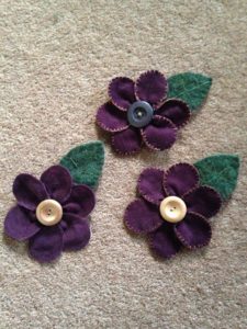 Purple cord flower and green felted wool leaf brooch with wooden button centre.