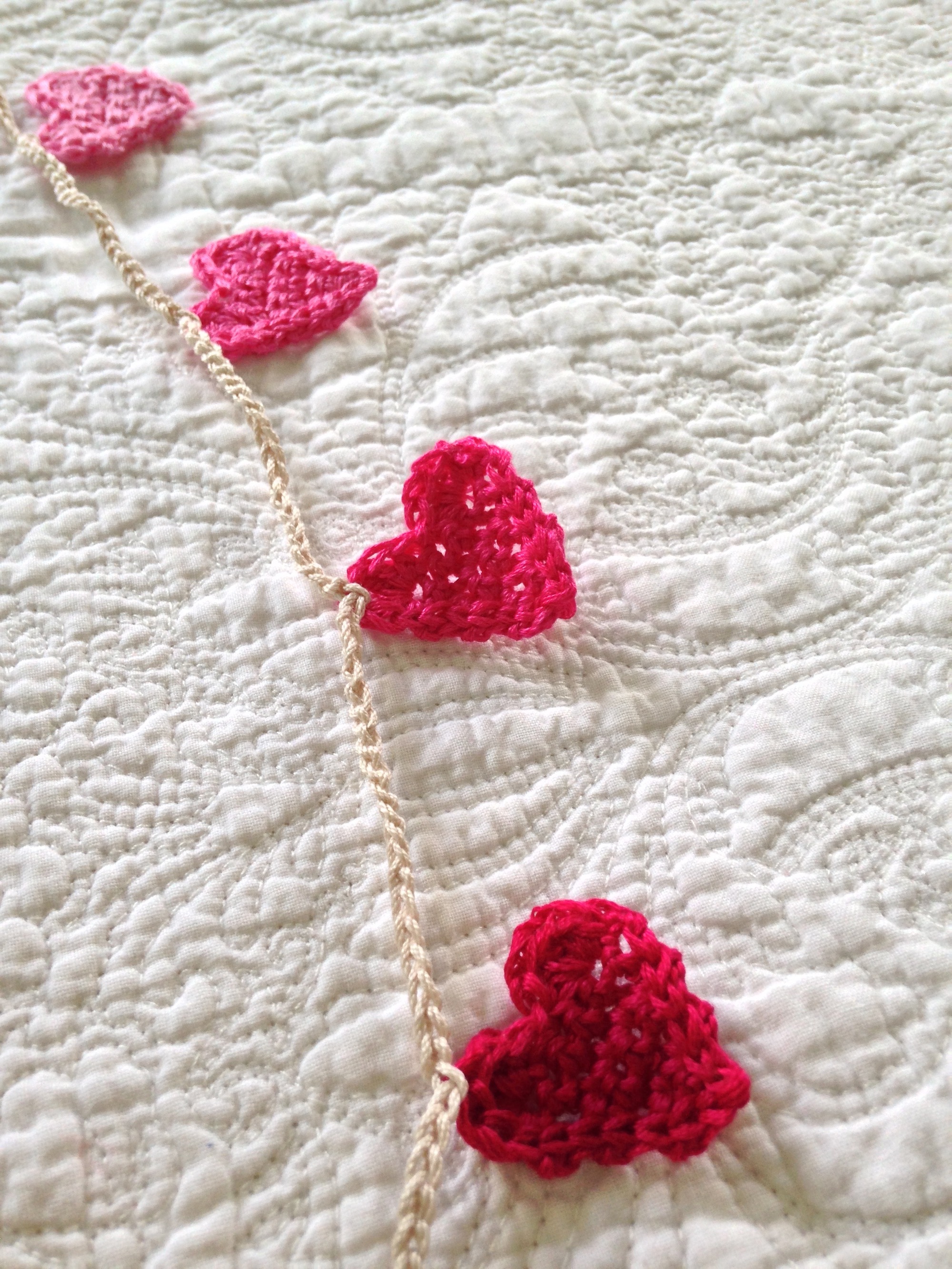 Tiny crocheted heart garland. A gradient of Dark red through to pink.