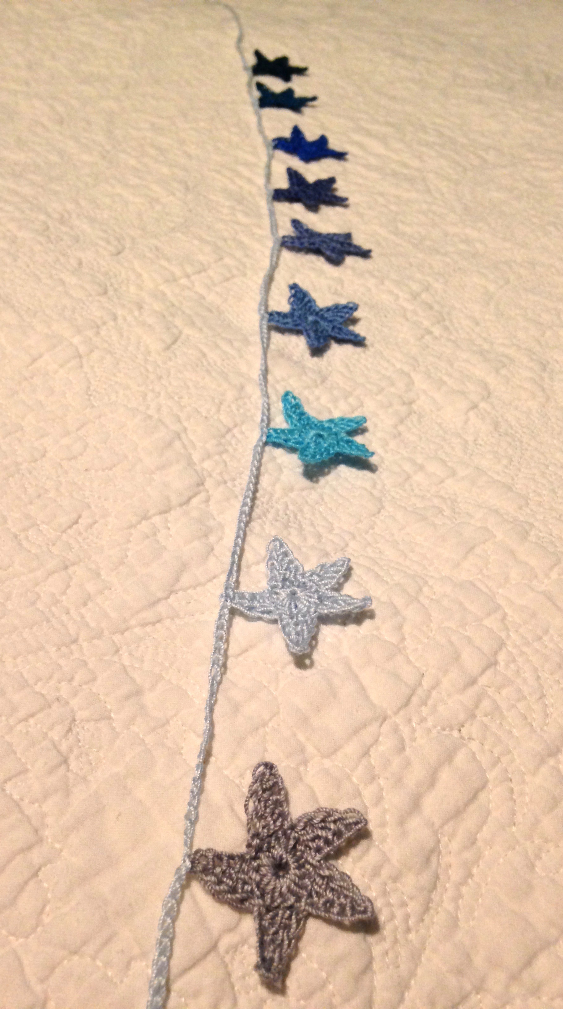Hand crocheted mini star garland. A gradient of nine blue toned stars.