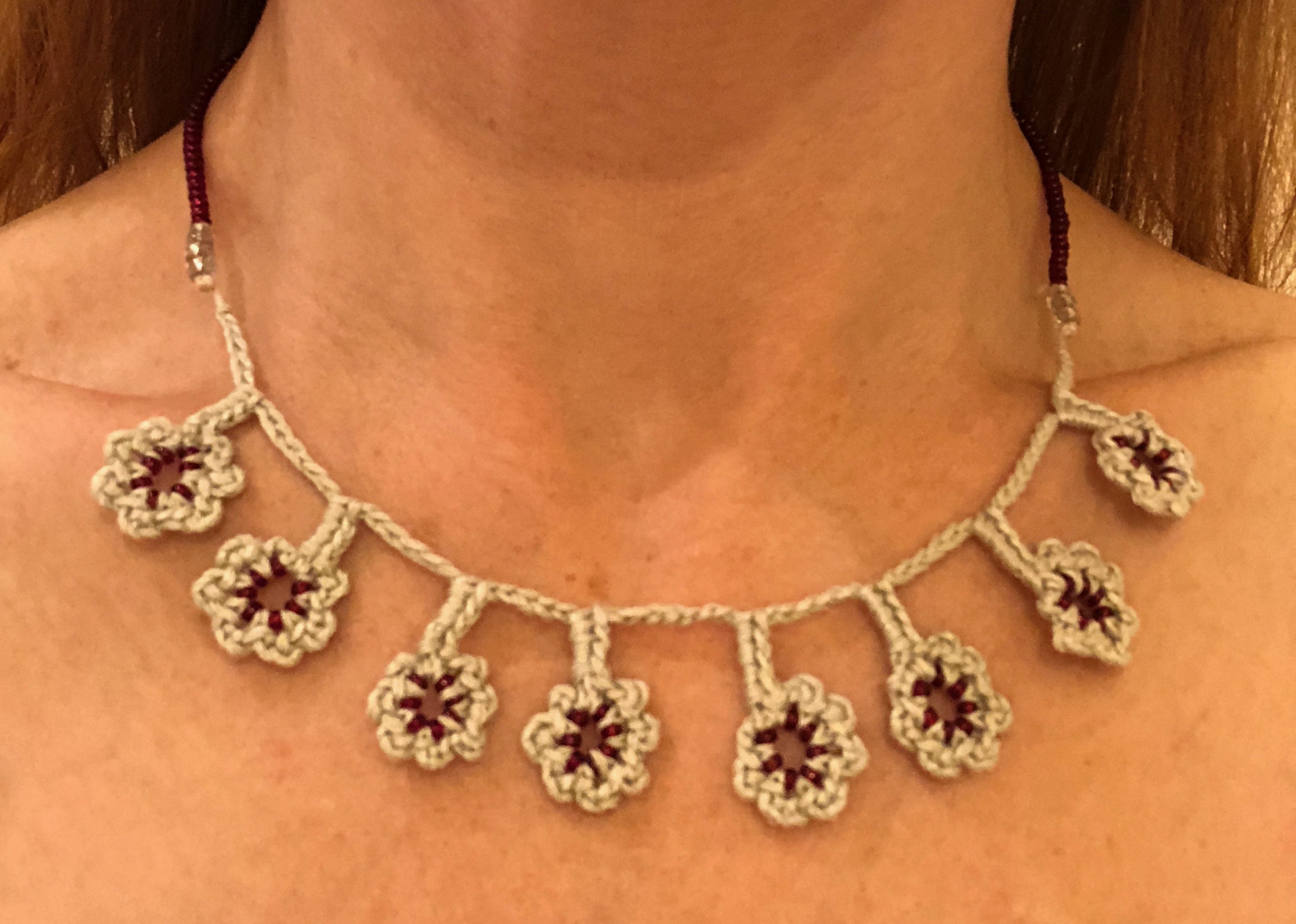 A grey cotton and burgundy red beaded hand crocheted flower necklace.