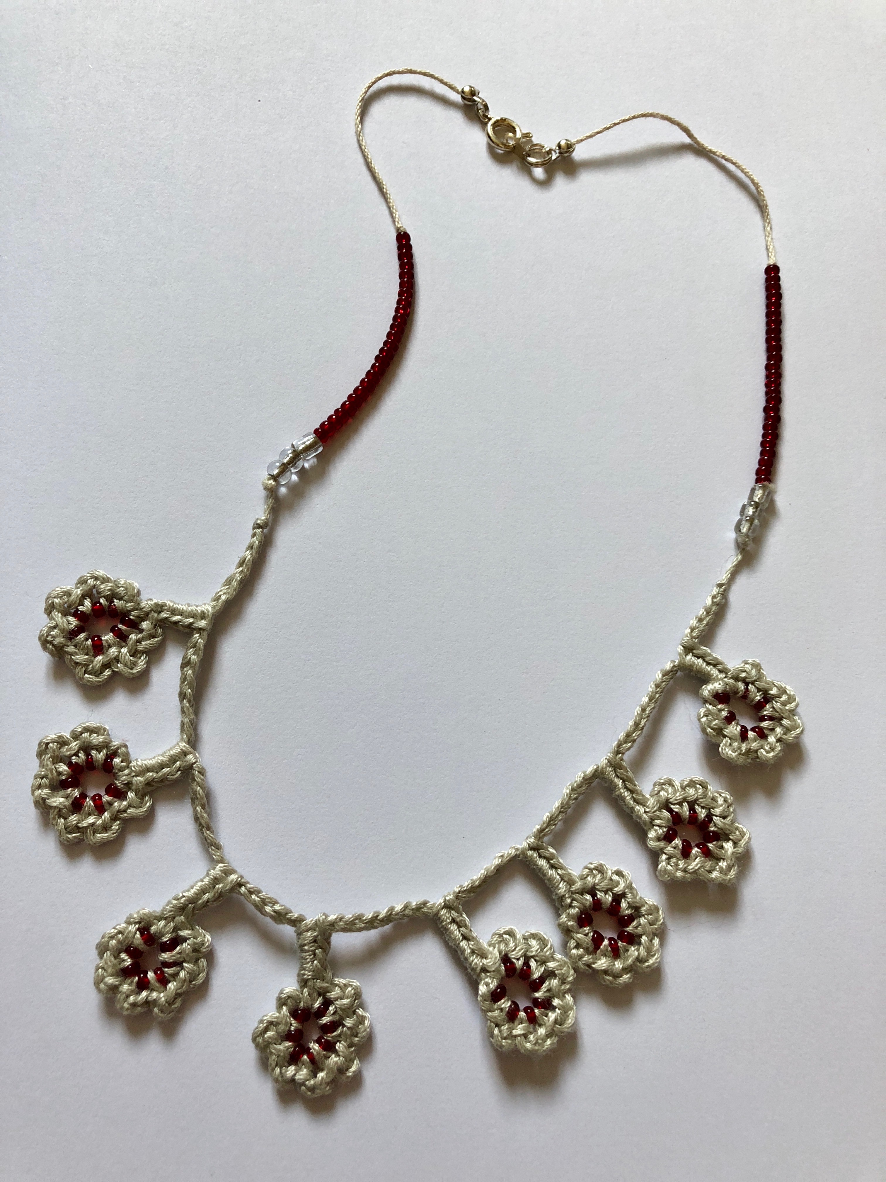 A grey cotton and burgundy red beaded hand crocheted flower necklace.