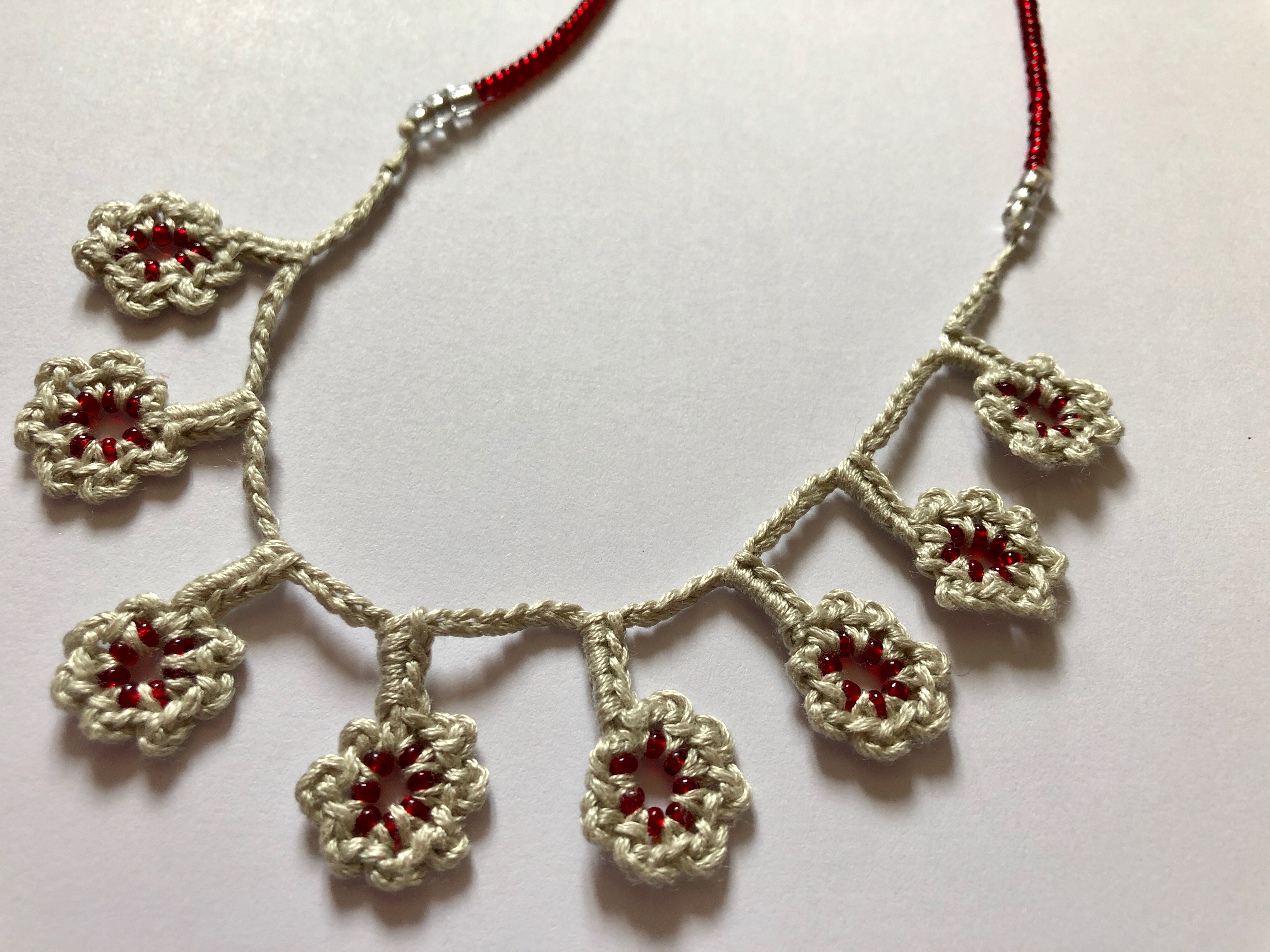A grey cotton and burgundy red beaded hand crocheted flower necklace.