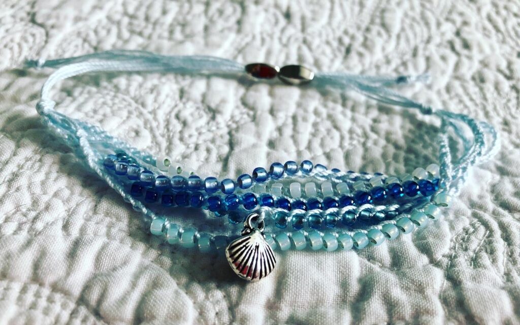 5 strand, fully adjustable bracelet with glass beads and silver metal coloured charm. Handmade using 100% cotton. Eco-friendly and fully recyclable.