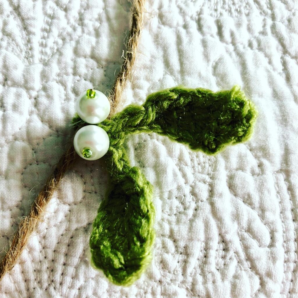 A hand crocheted mistletoe and beaded garland on jute.