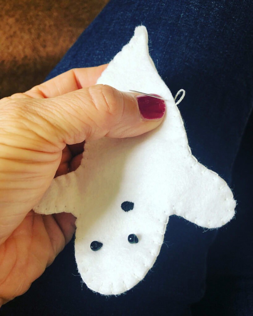 Hand stitched, white felt ghosts with hand embroidered facial details.