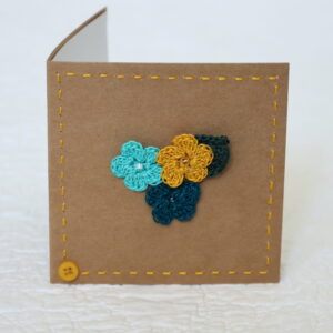 Posy of 3 crocheted flowers and a leaf with hand stitched border on a small brown card (approximate size 10 x 10 cm)with blank white insert. Brown envelope included.