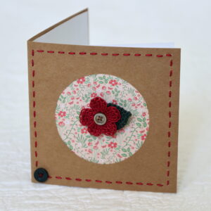 A single crocheted flower and a leaf with hand stitched border on a small brown card (approximate size 10 x 10 cm)with blank white insert. Brown envelope included.