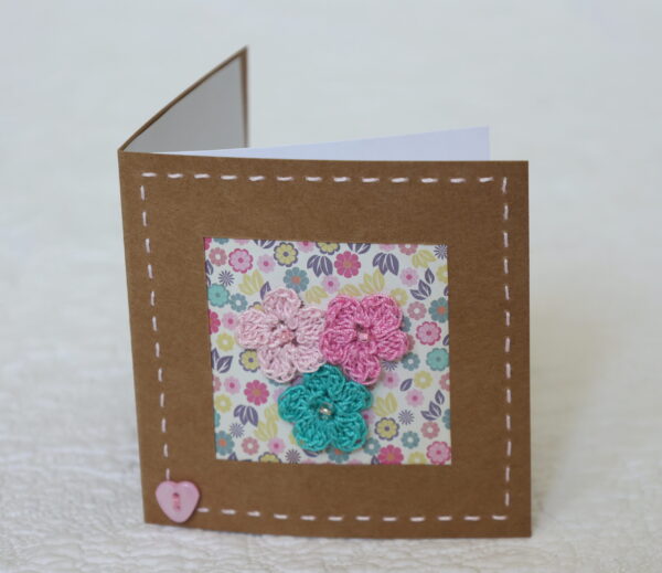Posy of 3 crocheted flowers with hand stitched border on a small brown card (approximate size 10 x 10 cm)with blank white insert. Brown envelope included.