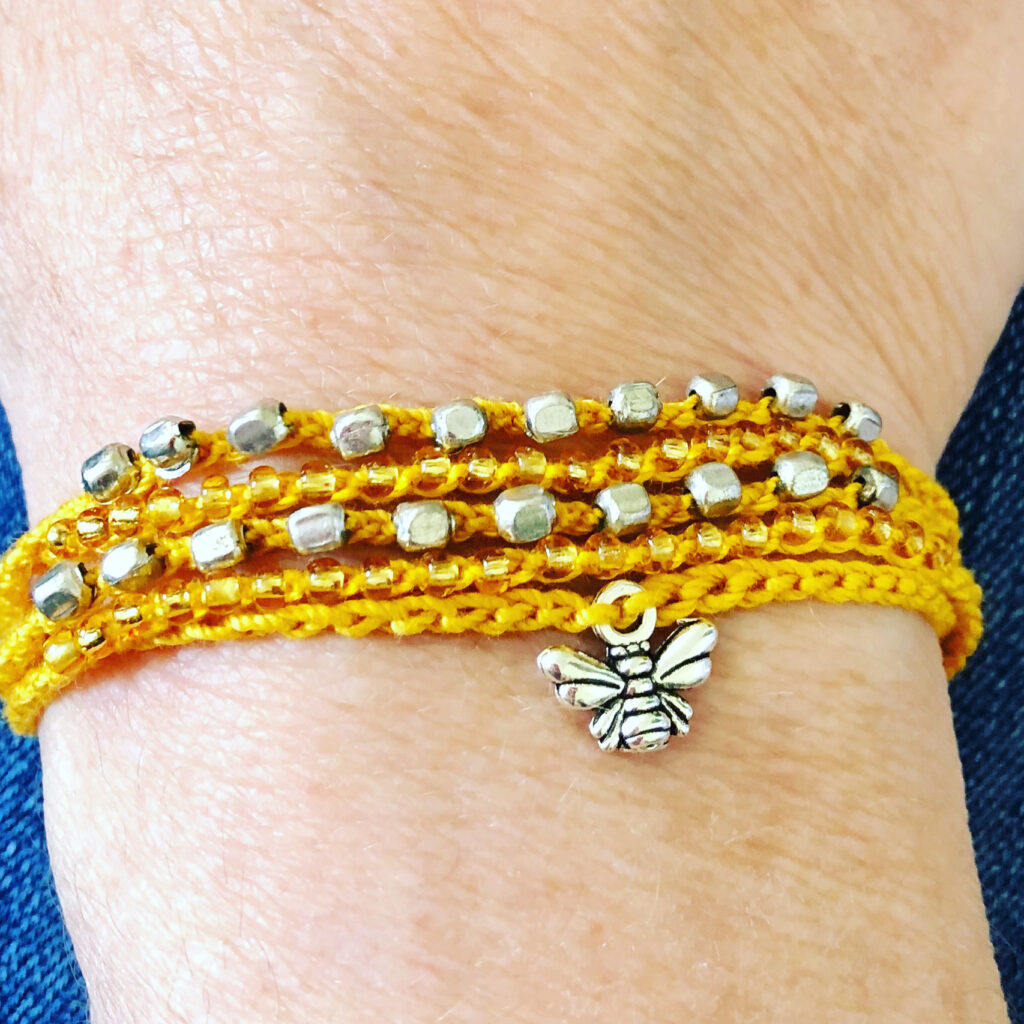 5 strand, fully adjustable bracelet with glass beads and silver metal coloured bee charm. Handmade using 100% cotton. Eco-friendly and fully recyclable.