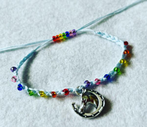 Single strand, fully adjustable bracelet with glass beads and silver metal coloured charm. Handmade using 100% cotton. Eco-friendly and fully recyclable.