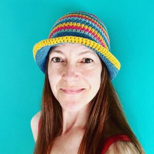 A hand crocheted bucket style hat, made using 100% cotton. It has multi coloured stripes in 3 bright colours, Turquoise, Mustard yellow and pink. One size.
