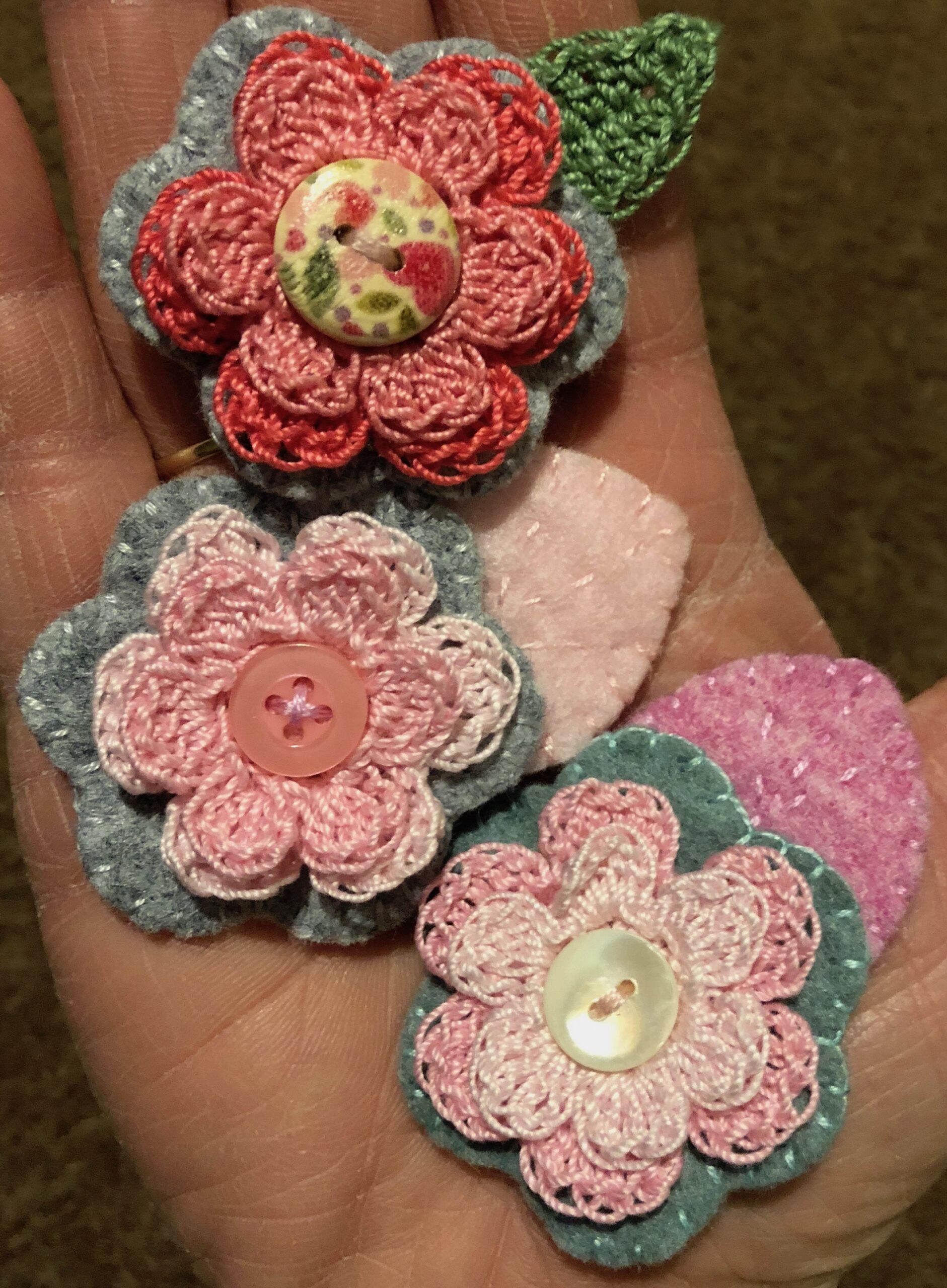 A hand-full of little flower brooches.