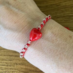 A red ceramic heart and clear glass beaded bracelet on a red crocheted cotton strap, with a fully adjustable sliding fastening.