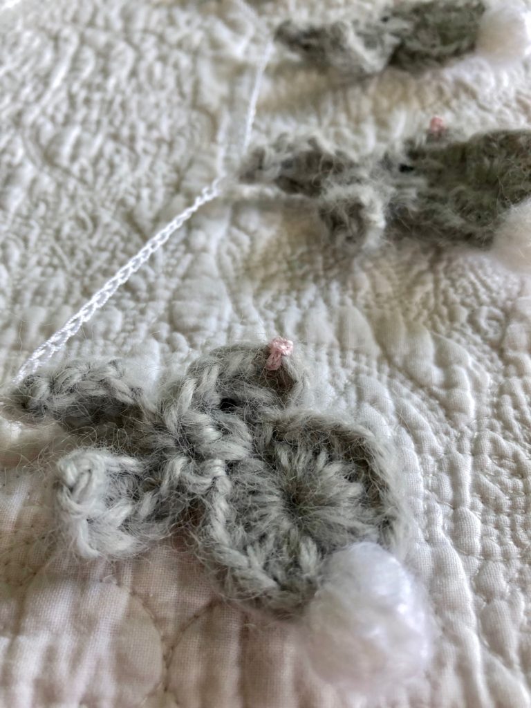 A garland of small, grey mohair, crocheted bunny rabbits with pom-pom tails. 