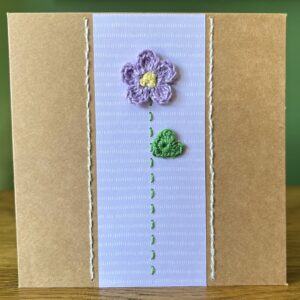 A single crocheted Lilac flower and green leaf, with a hand stitched detailing. This medium brown card has a blank white insert for your own message, and an envelope is included. Approximate size 12.5cm x 12.5 cm. Made using 100% cotton. Eco-friendly, Vegan friendly and fully recyclable.