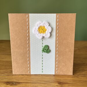 A single crocheted White flower and green leaf, with a hand stitched detailing. This medium brown card has a blank white insert for your own message, and an envelope is included. Approximate size 12.5cm x 12.5 cm. Made using 100% cotton. Eco-friendly, Vegan friendly and fully recyclable.