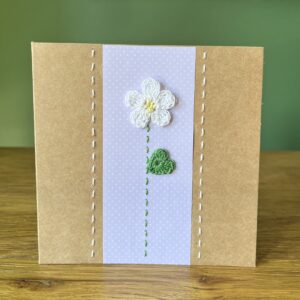 A single crocheted White flower and green leaf, with a hand stitched detailing. This medium brown card has a blank white insert for your own message, and an envelope is included. Approximate size 12.5cm x 12.5 cm. Made using 100% cotton. Eco-friendly, Vegan friendly and fully recyclable.