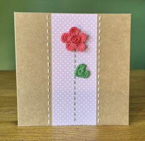 A single crocheted bright pink flower and green leaf, with a hand stitched detailing. This medium brown card has a blank white insert for your own message, and an envelope is included. Approximate size 12.5cm x 12.5 cm. Made using 100% cotton. Eco-friendly, Vegan friendly and fully recyclable.