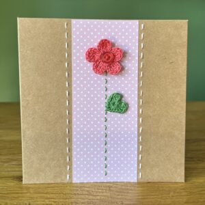 A single crocheted bright pink flower and green leaf, with a hand stitched detailing. This medium brown card has a blank white insert for your own message, and an envelope is included. Approximate size 12.5cm x 12.5 cm. Made using 100% cotton. Eco-friendly, Vegan friendly and fully recyclable.