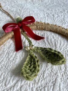 A large hanging wreath decoration. Handmade using 100% Jute on a natural wood ring. Decorated with 100% jute mistletoe, a velvet ribbon and wool felt balls. The beads are glass. No plastic has been used! Eco-Friendly, reusable and fully recyclable. Approximate size is 22cm circ, excluding hanging string. 