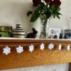 A hand crocheted garland of 10 snowflakes and glass beads, made in 100% white cotton. Approximate length 121cm.