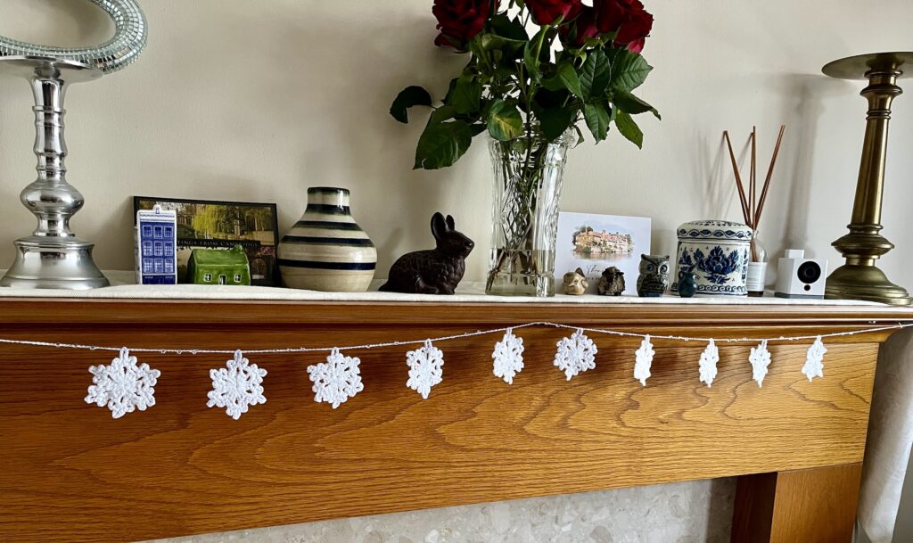 A hand crocheted garland of 10 snowflakes and glass beads, made in 100% white cotton. Approximate length 121cm.