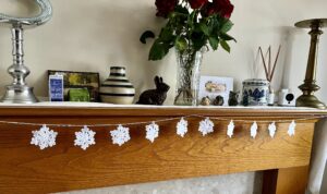 A hand crocheted garland of 10 snowflakes and glass beads, made in 100% white cotton. Approximate length 121cm.