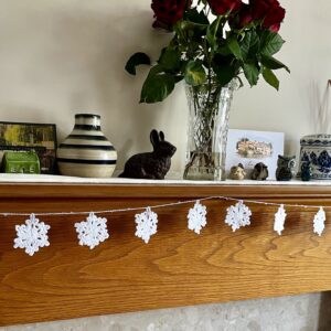 A hand crocheted garland of 10 snowflakes and glass beads, made in 100% white cotton. Approximate length 121cm.