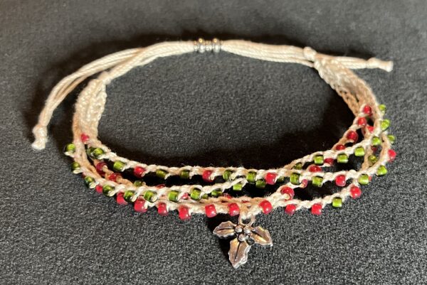 A 4 stranded, fully adjustable, red and green glass and metal beaded bracelet with silver coloured metal Holly charm. Made from 100% Cotton, glass and metal beads and a metal charm. No plastic! Eco-friendly, vegan friendly and completely recyclable.