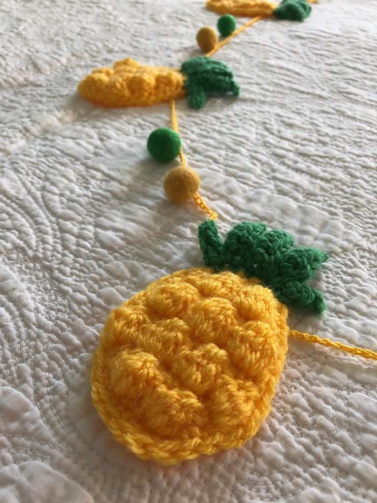 Hand crocheted yellow and green pineapple garland with green and yellow felt pompoms.