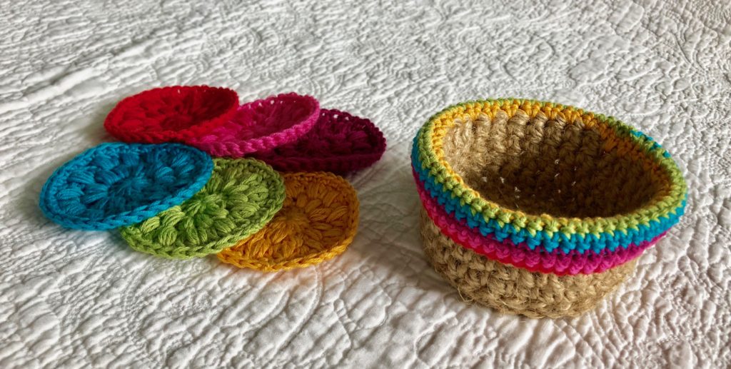 A hand crocheted 100% natural jute basket with  100% cotton crocheted edging detail containing a set of 6 100% cotton crocheted facial pads.