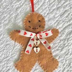 A hand-cut and handmade gingerbread man hanging decoration. Made in felt, with wooden buttons, glass beads, and ribbon details. Approximate size 11cm height (not including the hanging ribbon).