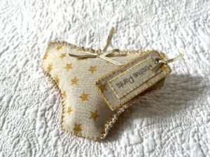 Gold star fabric, positive pants hanging decoration. A handmade, fabric and felt hanging decoration, with crocheted edging and ribbon bow, a positive pants label and hanging ribbon.