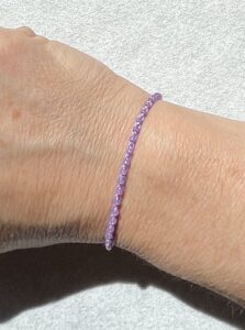 A handmade, crocheted, single stranded bracelet. Made using glass beads and 100% cotton both in a pastel purple/Lilac colour with a fully adjustable sliding bead fastening.