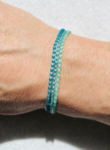 A handmade, crocheted and glass beaded bracelet. Fully adjustable with sliding glass bead fastening. 3 strands, made using 100% cream cotton and glass beads in 3 shades of green.