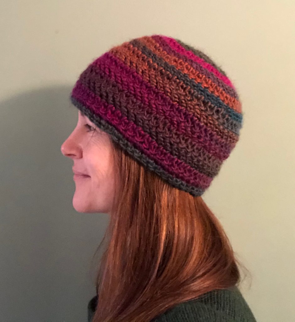 An autumn inspired, multi coloured, crocheted hat with a black fleece lined ear warmer band.