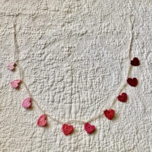 A crocheted garland of tiny hearts in a gradient of pale pink through to burgundy red.