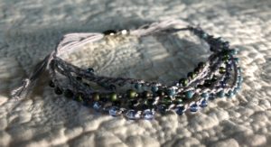 A multi stranded, grey crocheted cotton and glass seed bead bracelet. Using tones of blue and grey glass beads.