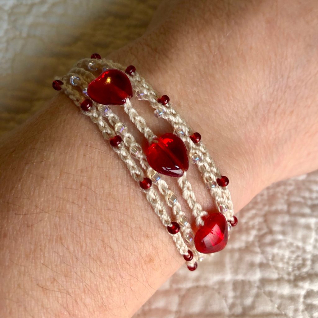 Cream Cotton, crocheted, multi stranded, adjustable bracelet with glass heart and seed beads.